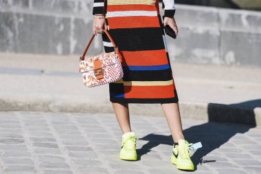 Paris, France - February 27, 2019: Street style outfit -  Women wearing sunglasses, a crochet colorfully striped dress, a white bag with orange spots , neon green Nike sneakers before a fashion show during Paris Fashion Week - PFWFW19 clipart