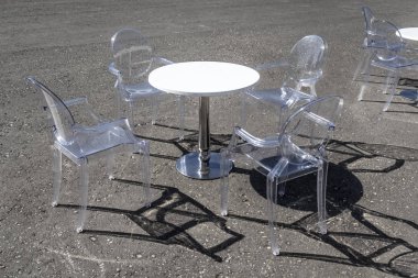 Sokakta şeffaf sandalyeler ile sehpa.