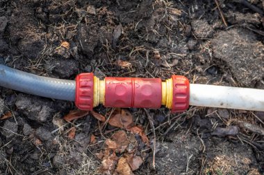 Bahçedeki kırmızı plastik sulama hortumu bağlantısı..