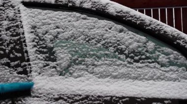 El fırçasıyla kardan arabanın camını temizliyorum..