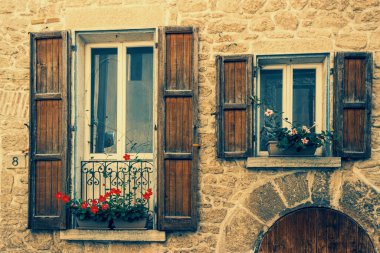 San Marino 'da ahşap panjurları olan antik bir taş binanın resmi.