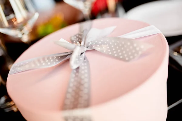 Caja de regalo redonda rosa con un lazo moteado en la mesa de la boda — Foto de Stock