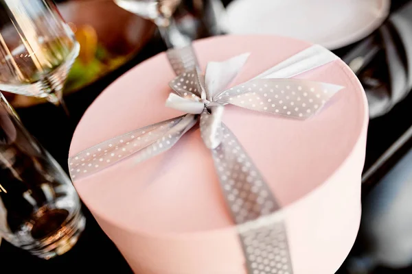 Caja de regalo redonda rosa con un lazo moteado en la mesa de la boda — Foto de Stock