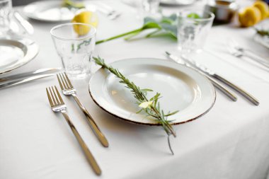 bir restoranda çiçekli beyaz masa örtüsü üzerinde cihazların hizmet