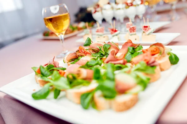 Bruschetto con tomate y albahaca en un plato y una copa de vino blanco —  Fotos de Stock