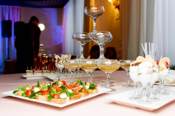 bir tabak domates ve mozzarella aperatifler, meyve aperatifler ve şampanya bardağı piramit şeklindeki 