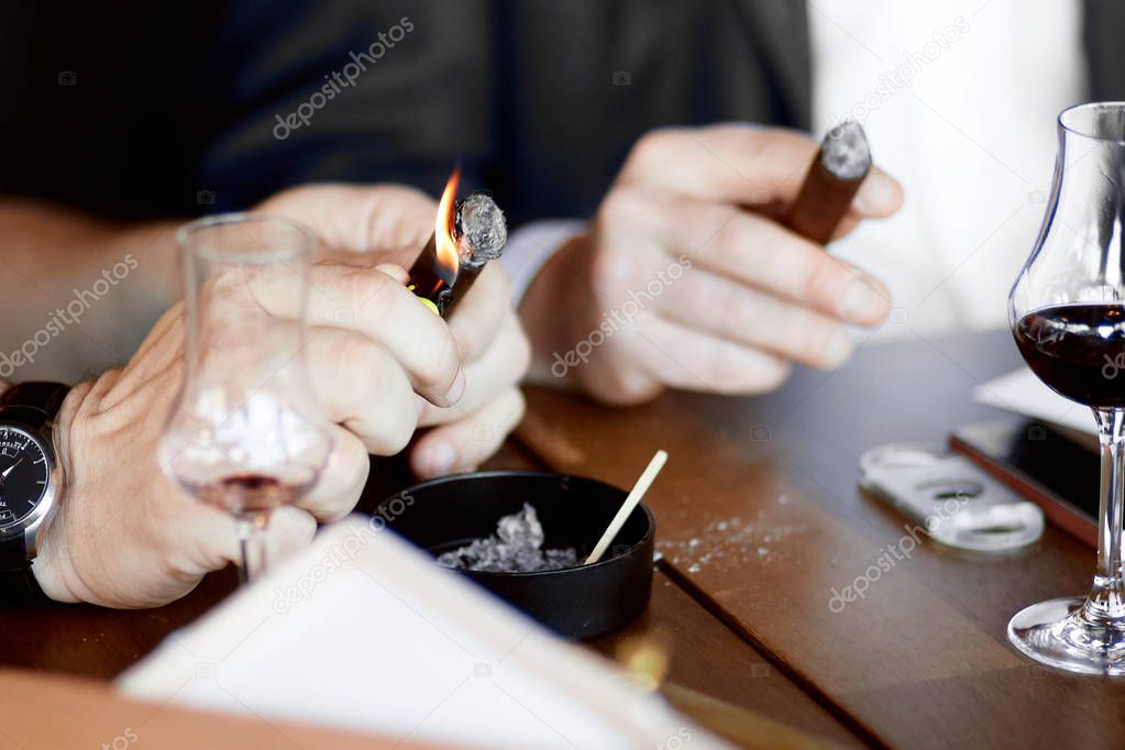 men's hands with a cigar and  glasses of mulled wine