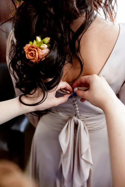 Vrouwelijke handen knop de trouwjurk aan de bruid — Stockfoto