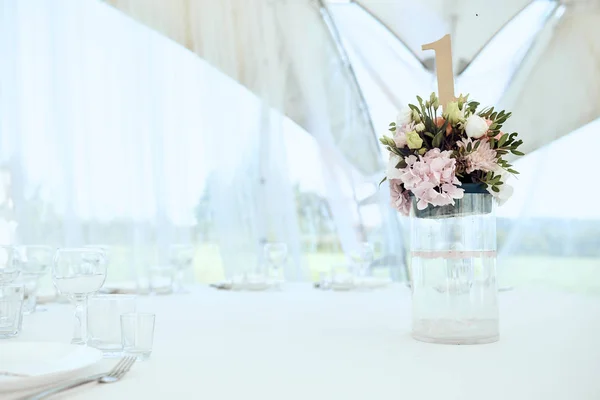 La plancha en forma del número de mesa que se encuentra en el ramo de flores en el florero sobre la mesa — Foto de Stock