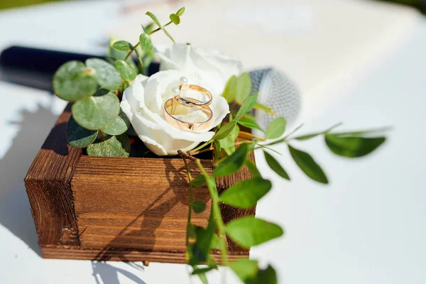 Iki alyans ahşap bir kutu içinde gül çiçekleri üzerinde yalan Stok Fotoğraf