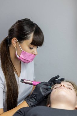 Güzellik uzmanı, sakin bir stüdyo ortamında müşterilere mikropatinaj tekniklerini titizlikle uygular. Müşteri rahatça uzanıyor, prosedür sırasında rahatlıyor..