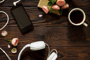Smartphone, kulaklık, kahve fincanı ahşap bir masa üzerinde. Üst görüntülemek düz yatıyordu arka plan. Kopya alanı