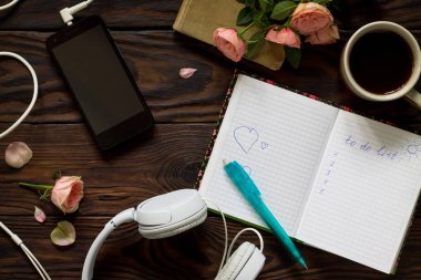 Kavramsal listelemek için. Smartphone, kulaklık, kahve fincanı ve ahşap bir masa üstünde defter. Üst görüntülemek düz yatıyordu arka plan.