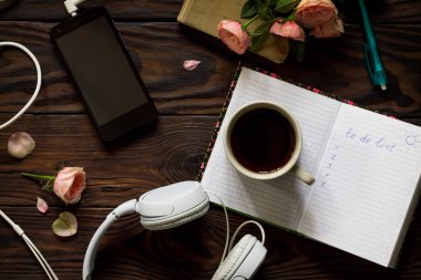 Kavramsal listelemek için. Smartphone, kulaklık, kahve fincanı ve ahşap bir masa üstünde defter. Üst görüntülemek düz yatıyordu arka plan.