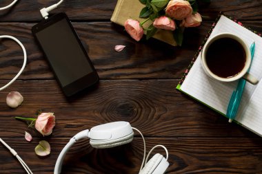 Smartphone, kulaklık, kahve fincanı ahşap bir masa üzerinde. Üst görüntülemek düz yatıyordu arka plan. Kopya alanı