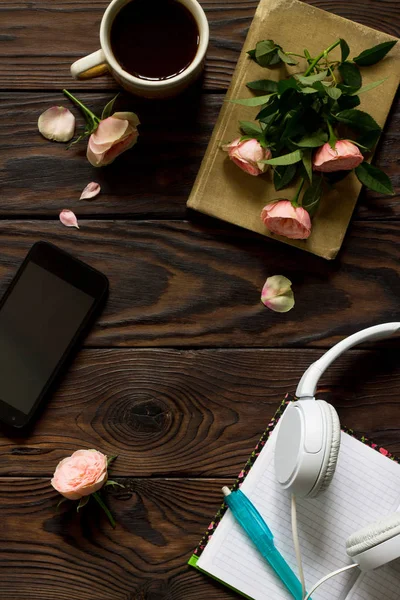 Smartphone, kulaklık, kahve fincanı ahşap bir masa üzerinde. Üst görüntülemek düz yatıyordu arka plan. Kopya alanı