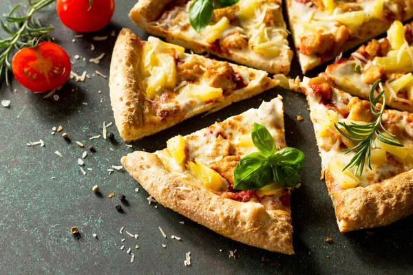 Pizza menu. Delicious hot Hawaiian pizza with chicken, pineapple and cheese. Delicious traditional Italian pizza on on a dark stone or concrete background.