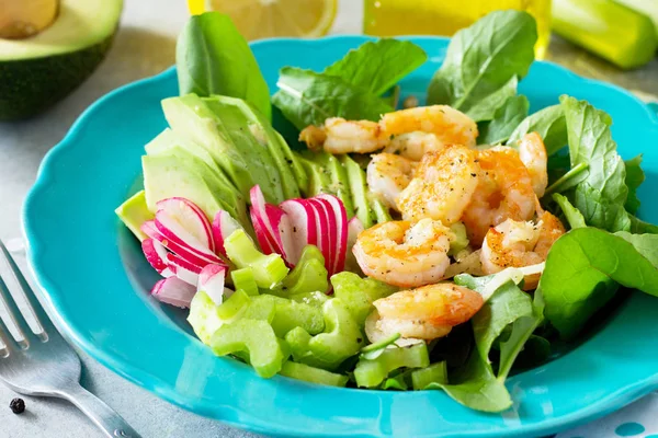 Izgara karides, rucola, turp, avokado, kereviz ve salata sosu ışık arduvaz arka plan üzerinde sağlıklı sebze salatası close-up. Diyet menüsü.