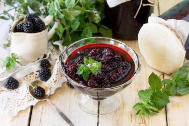 Ev yapımı reçel. Blackberry ve ahşap bir masa üzerine nane ile cam kavanoz. Korunmuş berry.