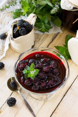 Ev yapımı reçel. Blackberry ve ahşap bir masa üzerine nane ile cam kavanoz. Korunmuş berry. Kopya alanı. 