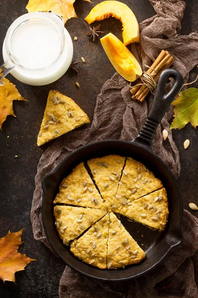 Traditional English cuisine. Breakfast table with pumpkin scones and milk on a stone or slate background, top view.