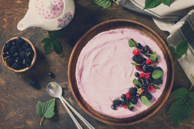Siyah frenk üzümü krem sufle ve Bisküvi pasta bir rustik tarzda bir masada. Üst görüntülemek düz yatıyordu arka plan. Uzay kopyalayın. Tonlu görüntü