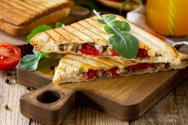 Kahvaltı kavramı. Meyve suyu ve lezzetli taze ev yapımı sandviçle ton balığı, domates, peynir bir ahşap mutfak masasında yakın çekim. 