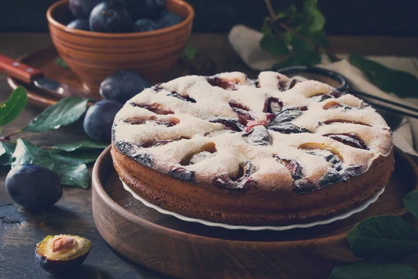 Delicious dessert plum pie, sweet delicious holiday cake with plums on wooden table. Toned image.