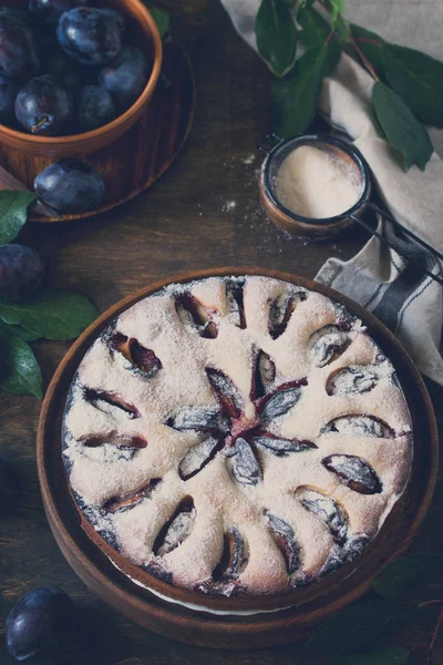 Delicious dessert plum pie, sweet delicious holiday cake with plums on wooden table. Copy space. Toned image