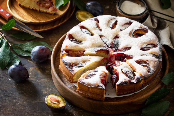 Delicious dessert plum pie, sweet delicious holiday cake with plums on wooden table.