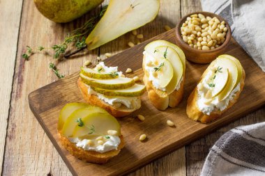 İtalyan Antipasti aperatifler şarap için. Yumuşak peynir, armut ve çam fıstığı ahşap bir masa üzerinde brushetta.