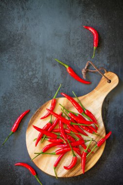 Bir ahşap tahta kesme, vintage taş arka plan üzerinde kırmızı acı biber Chili Peppers. Üst görüntülemek düz yatıyordu arka plan. Kopya alanı.