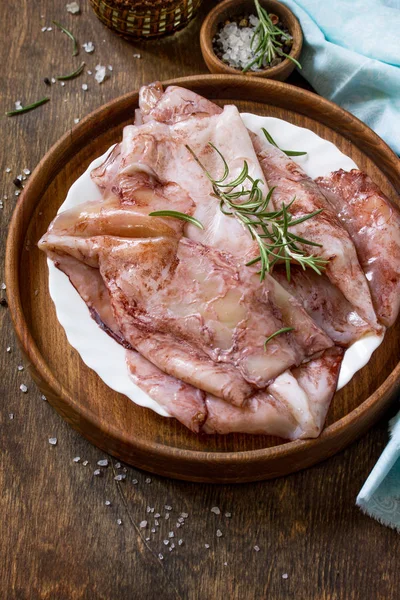 Taze kalamar, çeşitli baharat ve zeytinyağı ahşap bir masa üzerinde. Kopya alanı