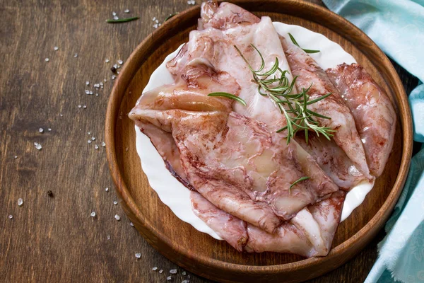 Taze kalamar, çeşitli baharat ve zeytinyağı ahşap bir masa üzerinde. Kopya alanı