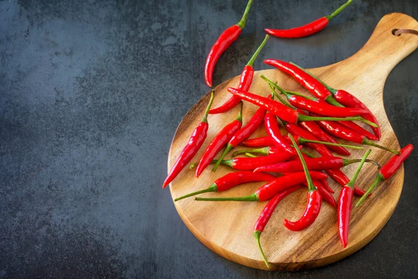 Bir ahşap tahta kesme, vintage taş arka plan üzerinde kırmızı acı biber Chili Peppers.