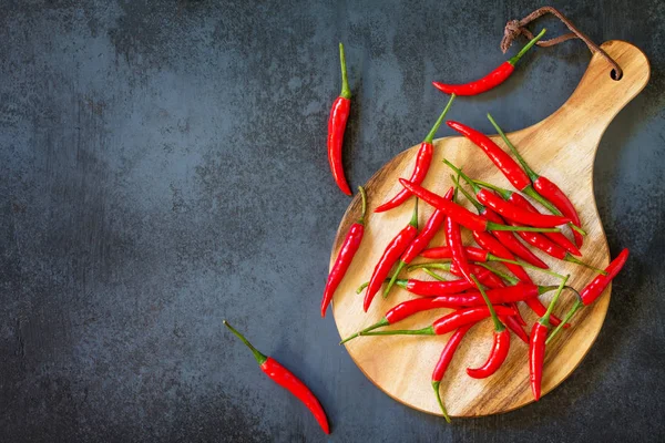 Bir ahşap tahta kesme, vintage taş arka plan üzerinde kırmızı acı biber Chili Peppers. Üst görüntülemek düz yatıyordu arka plan. Kopya alanı.