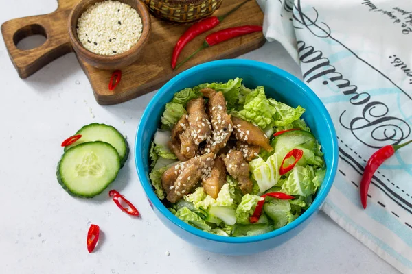 Diet menu. Healthy salad with Chinese cabbage, chicken, sesame and chili pepper on a white stone background.