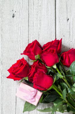 Düğün ya da Sevgililer günü, anneler günü kartı. Güzel kırmızı gül ve hediye kutusu ahşap tahta üzerinde çiçeklenme. Üst görüntülemek düz yatıyordu arka plan. Kopya alanı.
