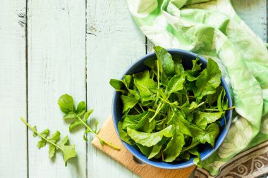 Taze salata roka mutfak ahşap bir masa üzerinde rustik bırakır. Üst görüntülemek düz yatıyordu arka plan. Kopya alanı.