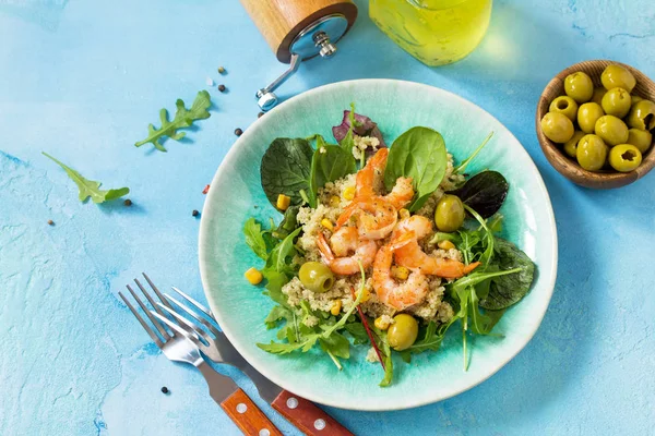 Diet menu, Vegan food. Healthy salad with quinoa, arugula, Shrimps and olives on a blue stone table. Copy space