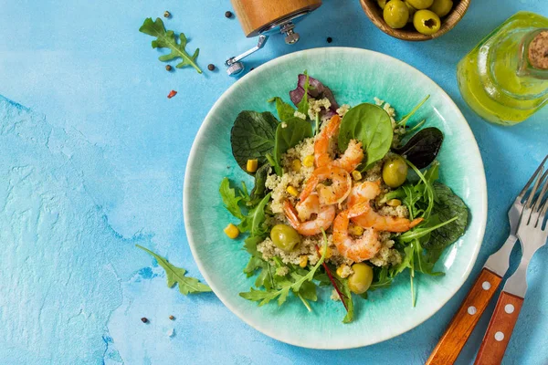Diet menu, Vegan food. Healthy salad with quinoa, arugula, Shrimps and olives on a blue stone table. Top view flat lay background. Copy space.