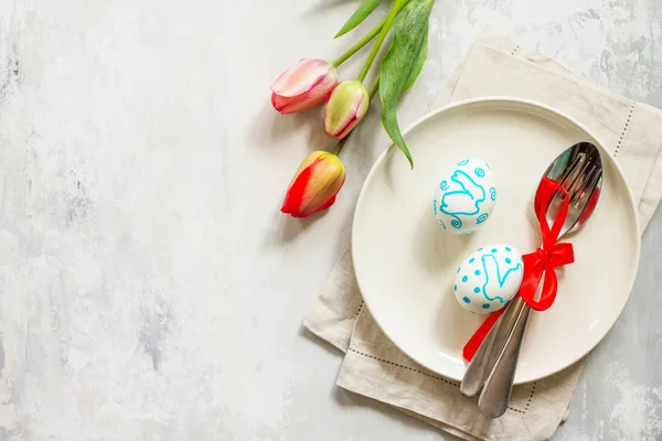 Easter table setting with tulips flowers, Easter eggs and cutlery. Holidays background. Top view flat lay background. Copy space.