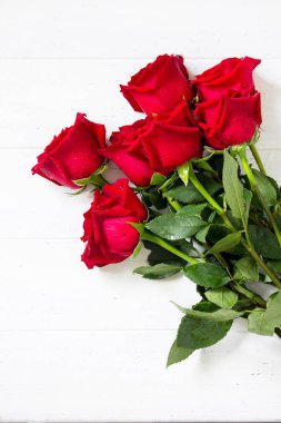 Düğün ya da Sevgililer günü, anneler günü kartı. Güzel kırmızı gül buketi Beyaz ahşap masa üzerinde çiçek. Düz yatıyordu, en iyi görünümü arka plan. Kopya alanı