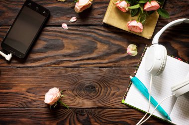 Bahar. Smartphone, kulaklık, kahve fincanı ahşap bir masa üzerinde. Üst görüntülemek düz yatıyordu arka plan. Kopya alanı.