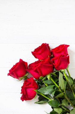 Düğün ya da Sevgililer günü, anneler günü kartı. Güzel kırmızı gül buketi Beyaz ahşap masa üzerinde çiçek. Düz yatıyordu, en iyi görünümü arka plan. Kopya alanı
