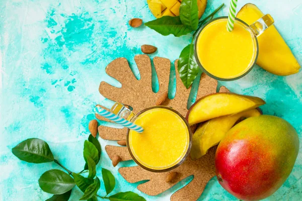 Superfoods and health or detox diet food concept. Fruit tropical smoothies in glass bottles with mango on stone table. Fresh organic Smoothie ingredients. Top view flat lay background. Copy space.