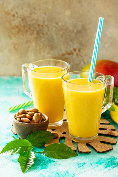 Superfoods and health or detox diet food concept. Fruit tropical smoothies in glass bottles with mango and Fresh organic Smoothie ingredients on stone table. Copy space