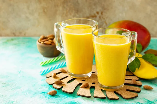 Superfoods and health or detox diet food concept. Fruit tropical smoothies in glass bottles with mango on stone table. Fresh organic Smoothie ingredients. Copy space.