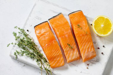 Taze balık. Çiğ somon fileto, limon ve beyaz bir taş masada ahşap bir gemide baharat. Üst görüntülemek düz yatıyordu arka plan. 