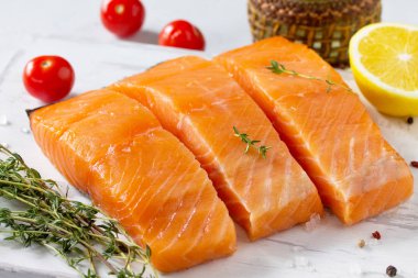 Taze balık. Çiğ somon fileto, limon ve beyaz bir taş masa ahşap bir gemide domates. 